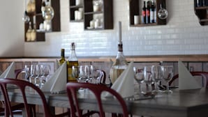 Comedor con una mesa lista para cuatro, copas y botellas de vino.
