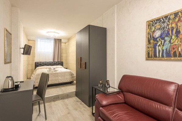 A hotel room with a bed, a desk, a leather sofa, and a painting on the wall. - Rifugio degli Artisti Top (Rome)