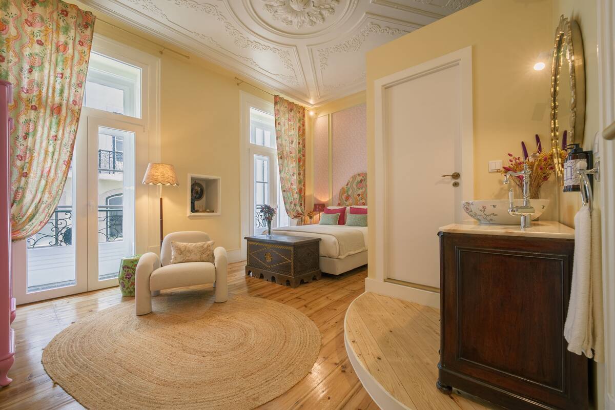 A room with a wooden floor, a round rug, a sofa, a small table, and a cabinet.