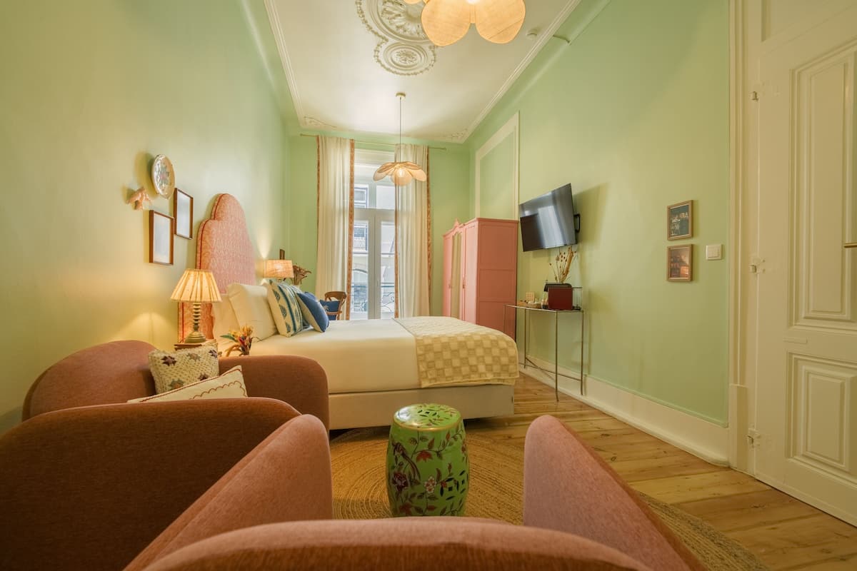 A bedroom with a bed, two chairs, a television, and a cabinet.