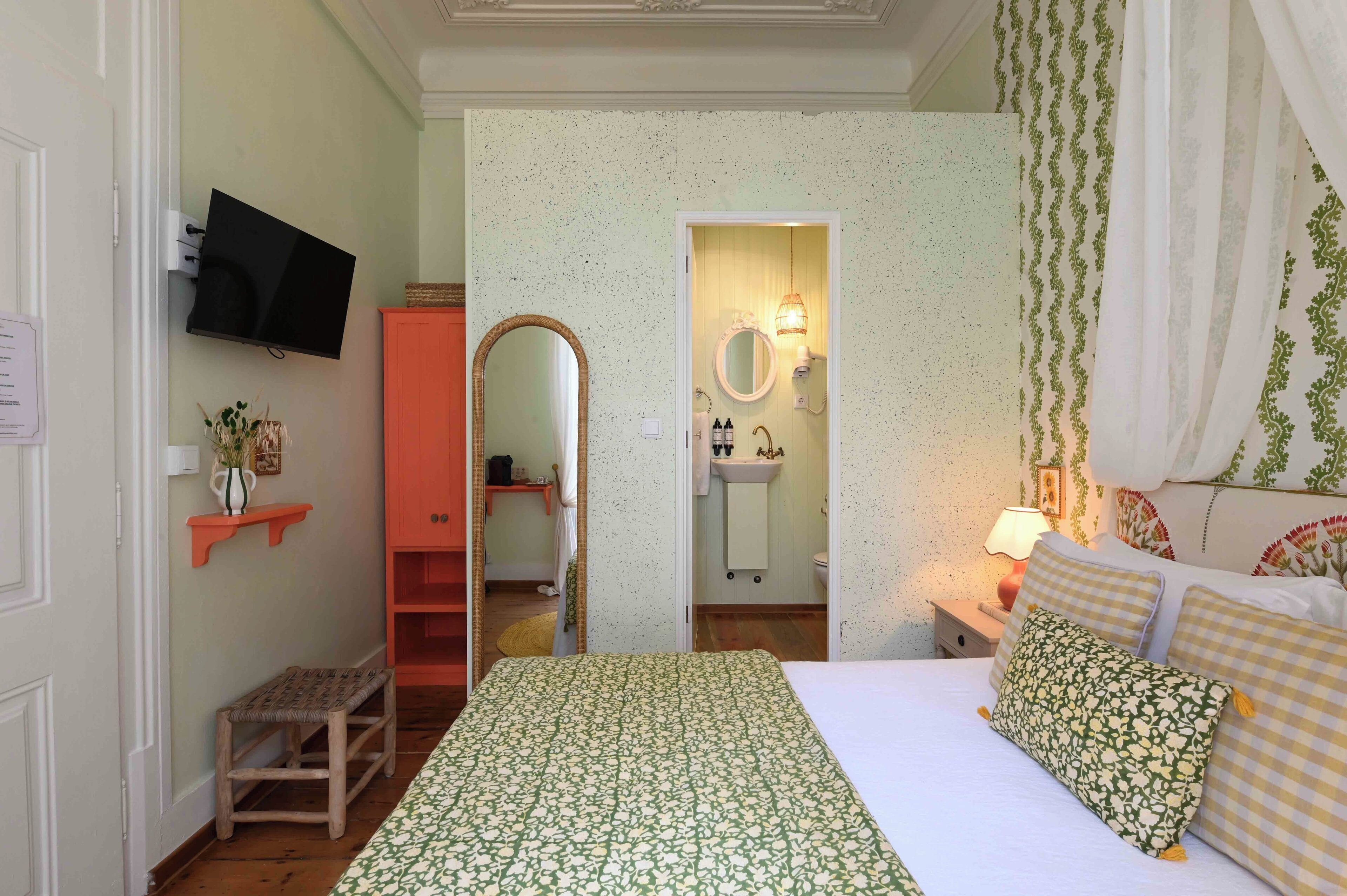 Ein Schlafzimmer mit Bett, Nachttisch mit Lampe, Spiegel und Kleiderschrank.