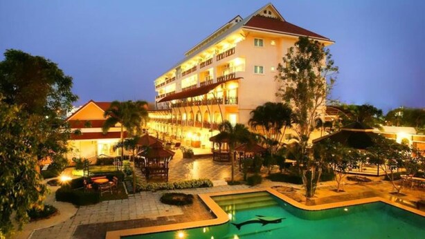 Hotel con piscina que presenta diseños de delfines, rodeado de abundante vegetación y un espacio exterior bien iluminado.