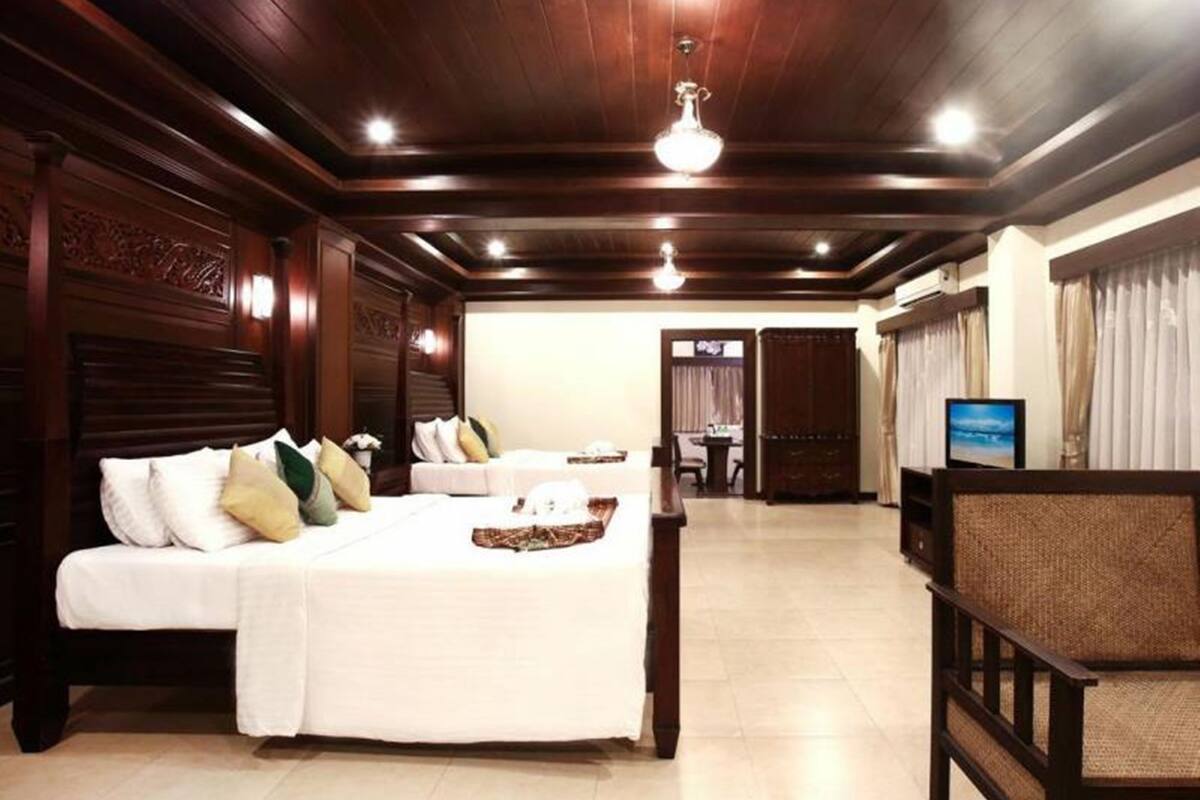 Une chambre d’hôtel avec deux lits, une télévision et un coin repas à l’arrière-plan.