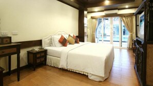 Habitación de hotel con una cama grande, una mesita de noche, piso de madera y vista al exterior a través de un ventanal.