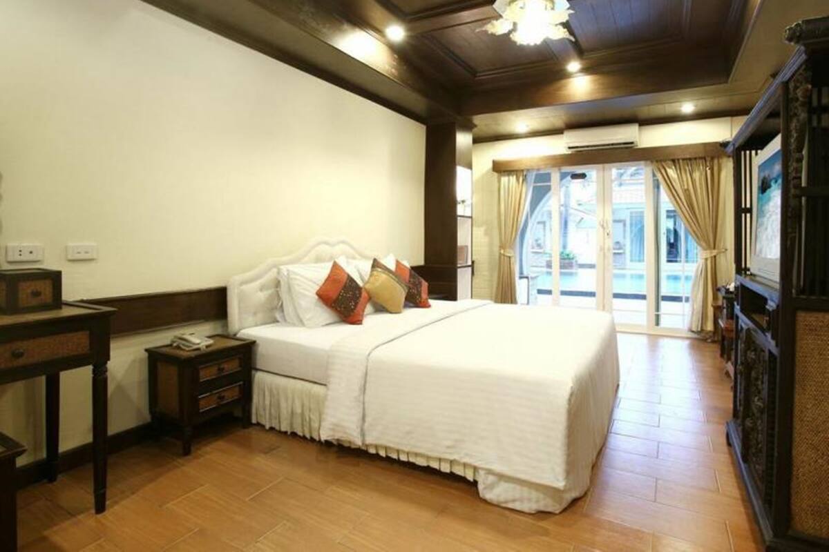 Une chambre d’hôtel avec un grand lit, une table de chevet, un plancher en bois et une vue sur l’extérieur grâce à une porte vitrée.