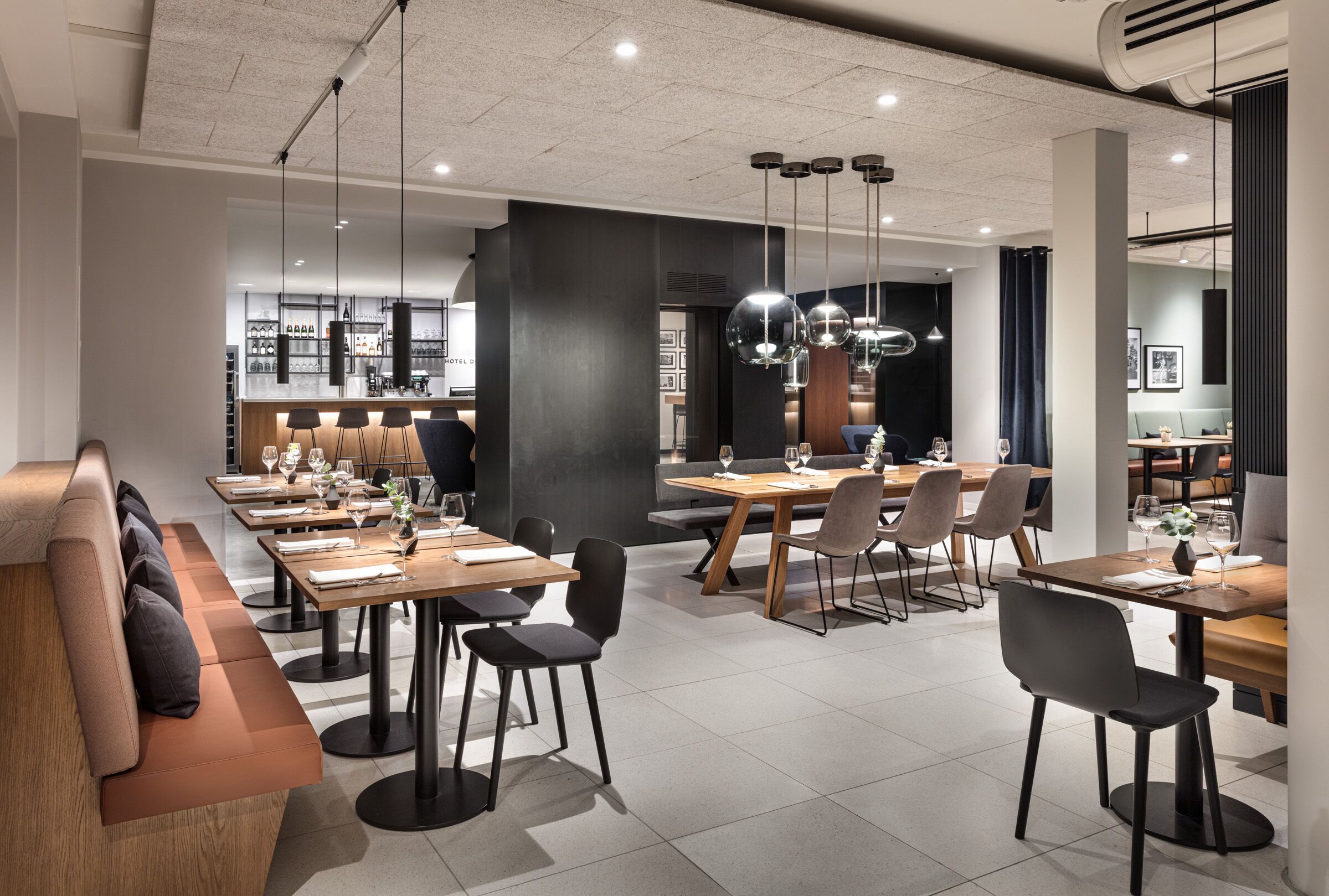 A modern restaurant with multiple dining areas, including a bar and a private dining room.