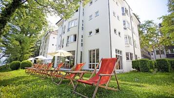 Un edificio de varios pisos con terraza al aire libre y un césped cuidado.