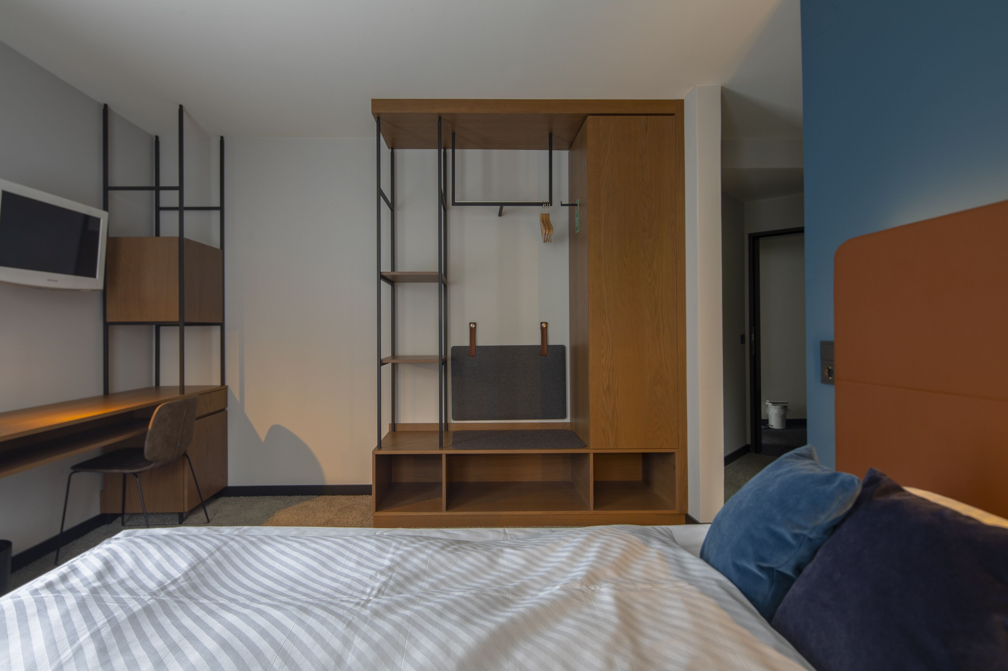 A modern bedroom with a bed, a desk, and a built-in wardrobe.
