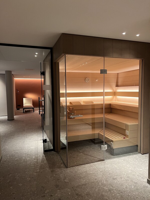 A modern room with a glass partition, a bed, and a seating area.