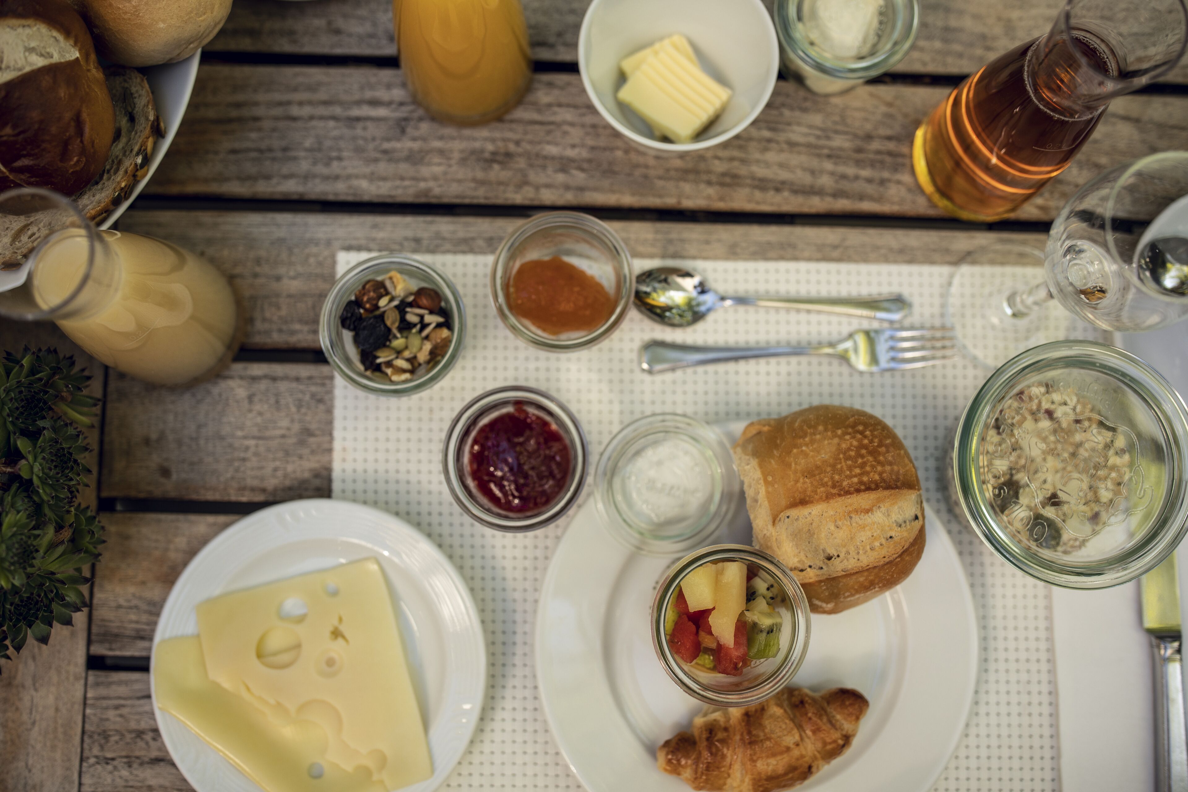 Une table garnie de divers aliments et condiments, notamment du pain, du fromage et des pots de tartinades.