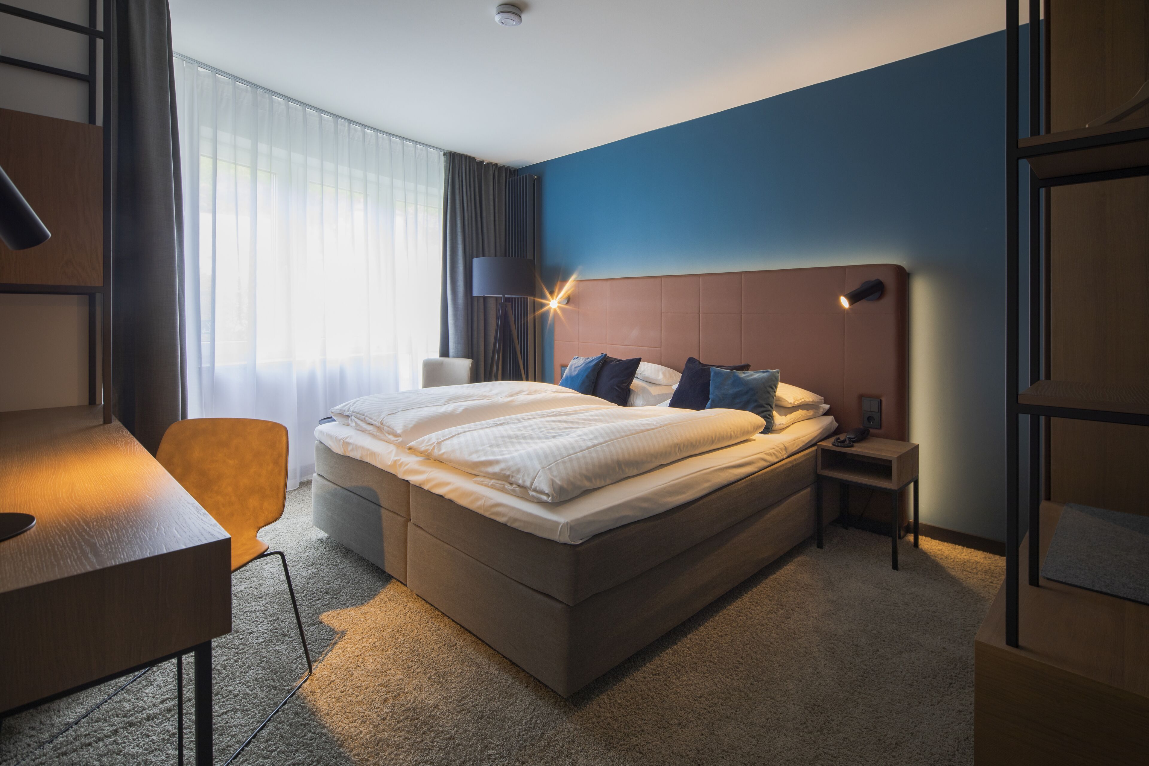 Ein modernes Hotelzimmer mit einem großen Bett, einem Schreibtisch und einem Sessel.