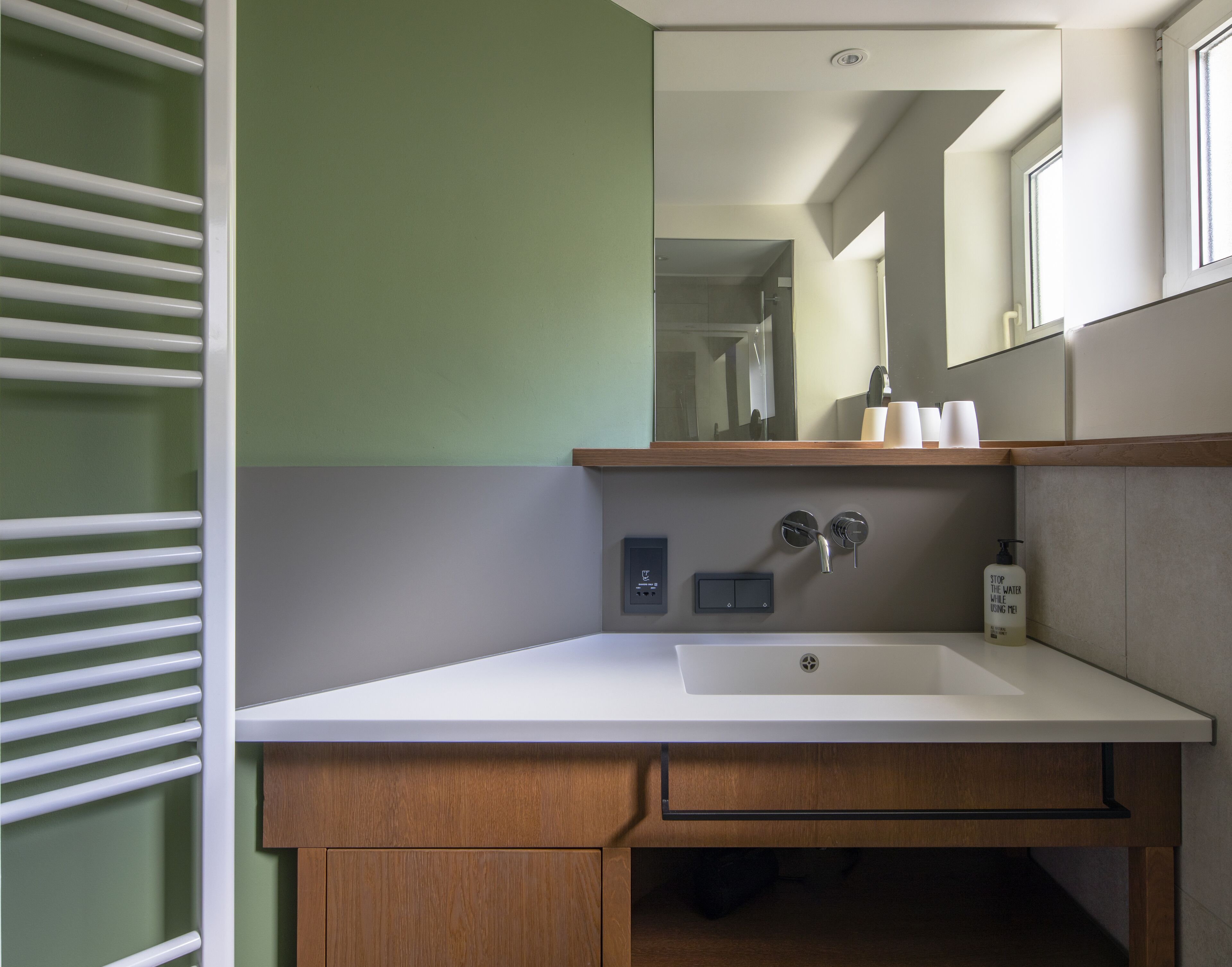 A modern bathroom with a white sink, wooden vanity, and a mirror above it.