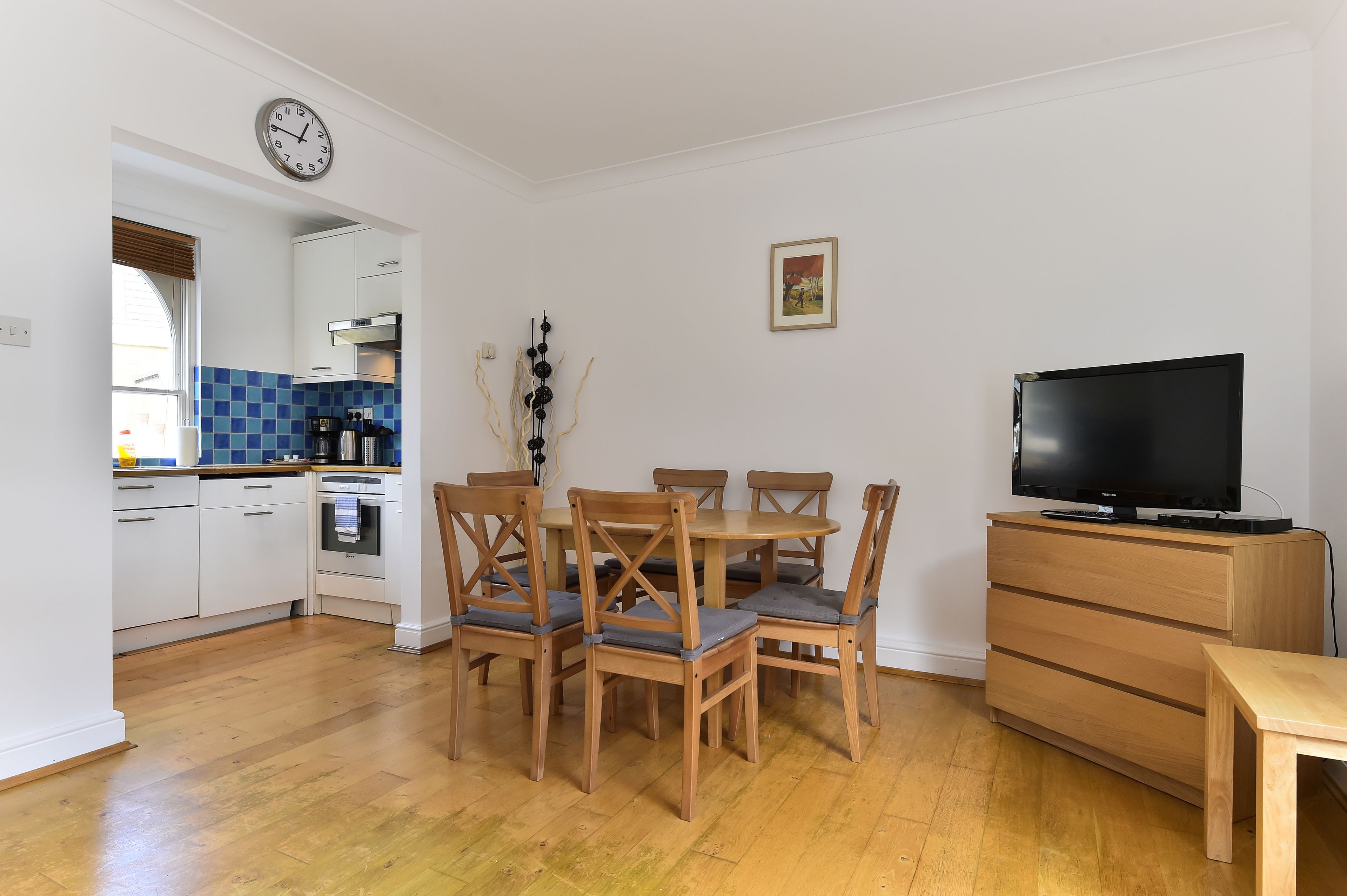 A compact living space with a dining area, kitchen, and a TV.