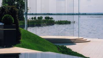 Un área de piscina exterior moderna con cerramiento de vidrio y una sombrilla amarilla.