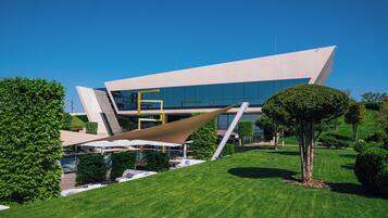 Un edificio moderno con un diseño angular único, rodeado de céspedes verdes y árboles bien cuidados.