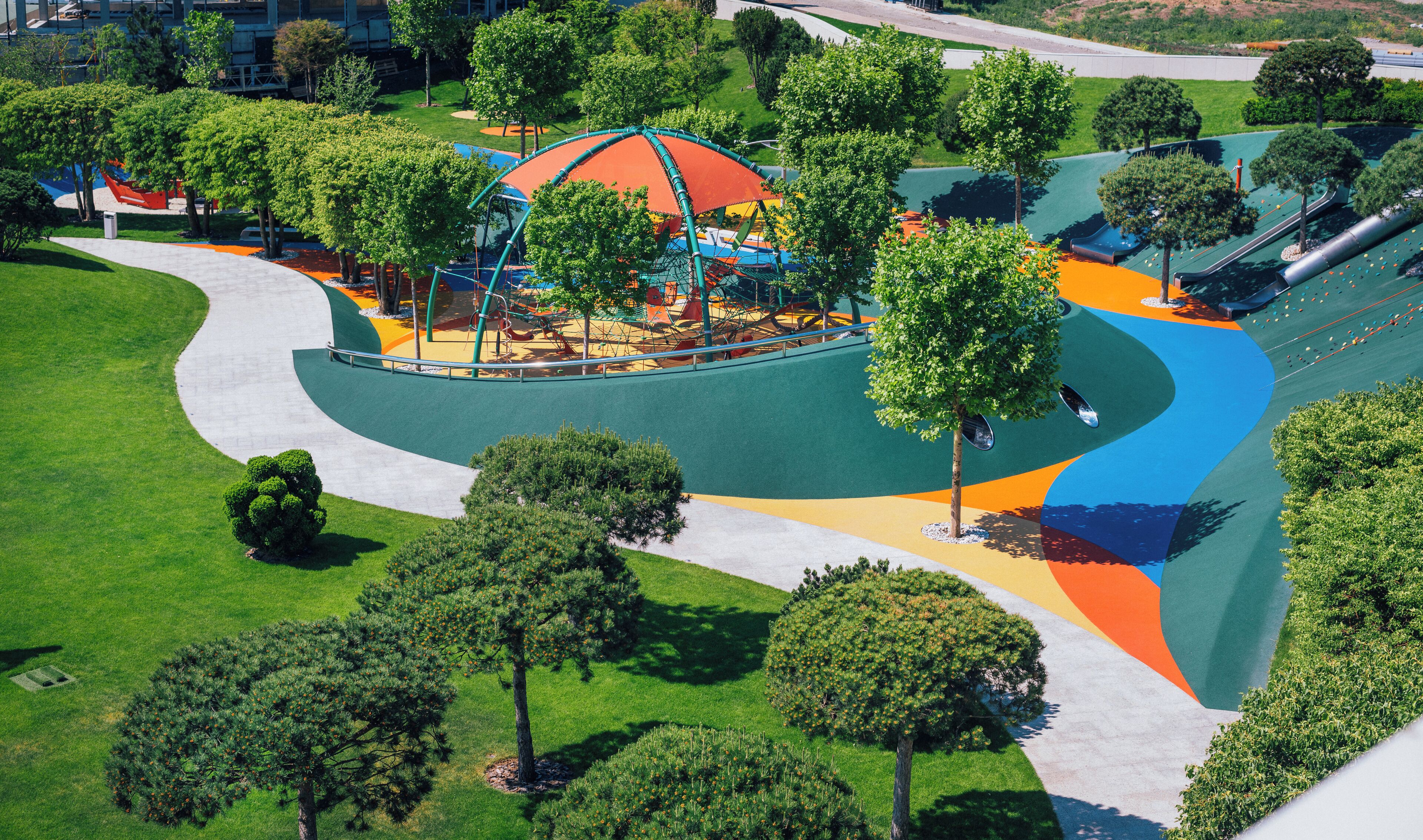 Vista aerea di un parco con un'area giochi, sentieri pedonali e ampi spazi verdi.