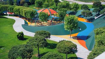 Vista aerea di un parco con un'area giochi, sentieri pedonali e ampi spazi verdi.