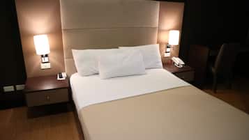 A hotel room with a large bed, two bedside tables with lamps, a nightstand, and a chair.
