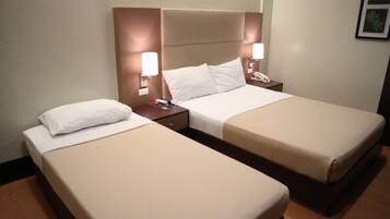 Una habitación de hotel con dos camas individuales, cada una con cabecero, mesitas de noche y lámparas.