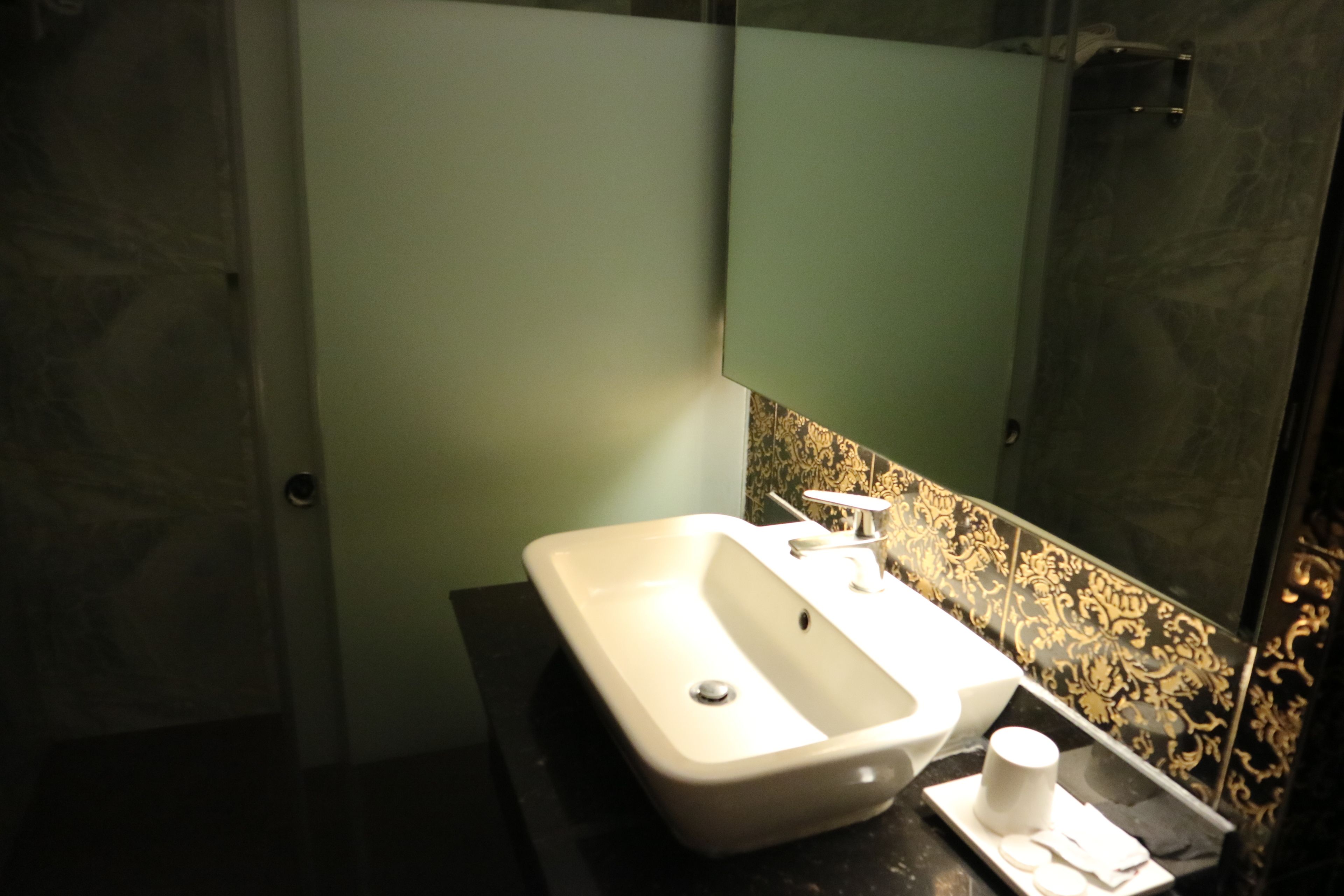 A bathroom with a white sink, a mirror, and a black countertop.