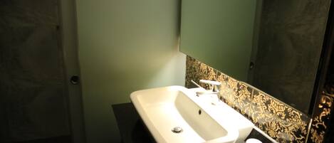 A bathroom with a white sink, a mirror, and a black countertop.