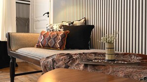 A modern living room with a sofa, patterned cushions, a decorative tray, and a vase with flowers.