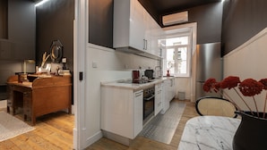 A modern kitchen with white cabinets, a marble countertop, and a view to the outside.