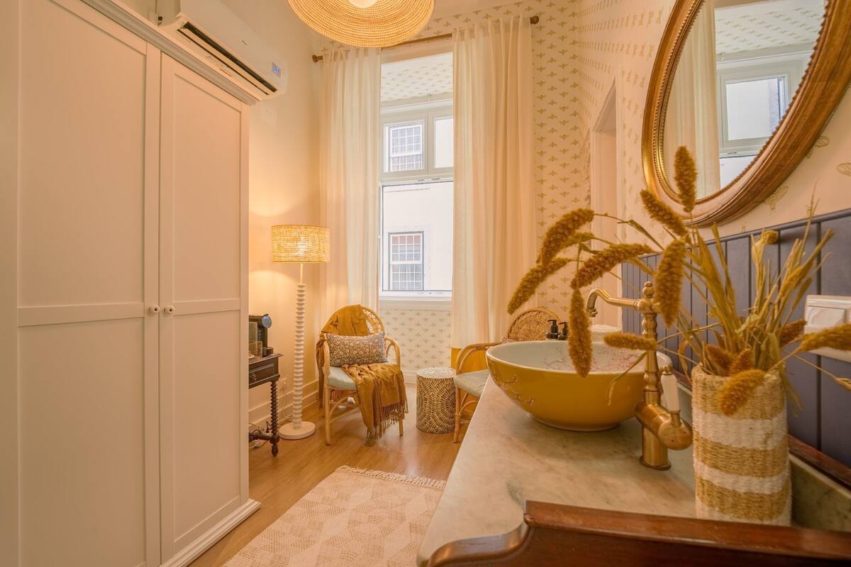 A bathroom with a large yellow sink, a mirror, and a wicker basket.