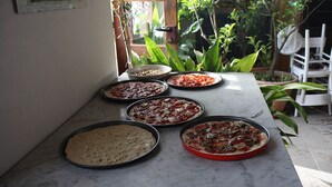 Una encimera de cocina con varios moldes de pizza que contienen diferentes tipos de pizza.