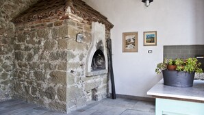 Una construcción de piedra con techo de tejas, una pequeña abertura y una planta en maceta sobre una mesa.