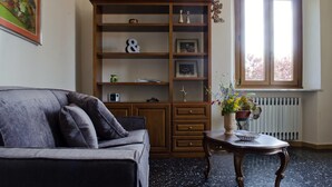 Una sala de estar con un sofá, estantería de madera y una mesa con un jarrón de flores.