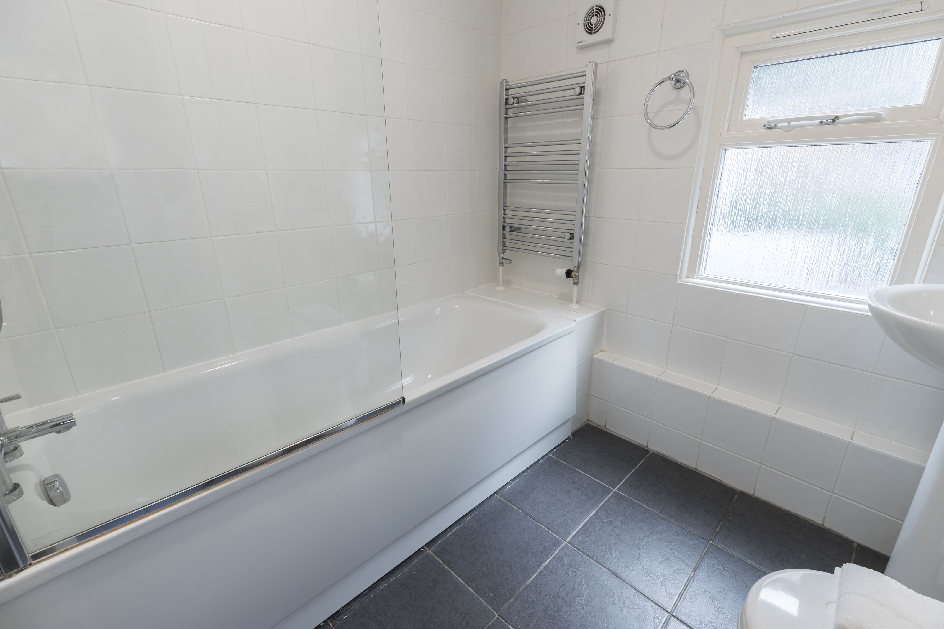 A modern bathroom with a white bathtub, a glass-enclosed shower, and a white sink.