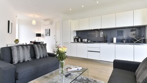Ein modernes Wohnzimmer mit einem grauen Sofa, einem Glastisch und einer Vase mit Blumen.