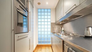 Eine moderne Küche mit Edelstahlgeräten, einem großen Fenster und Holzboden.