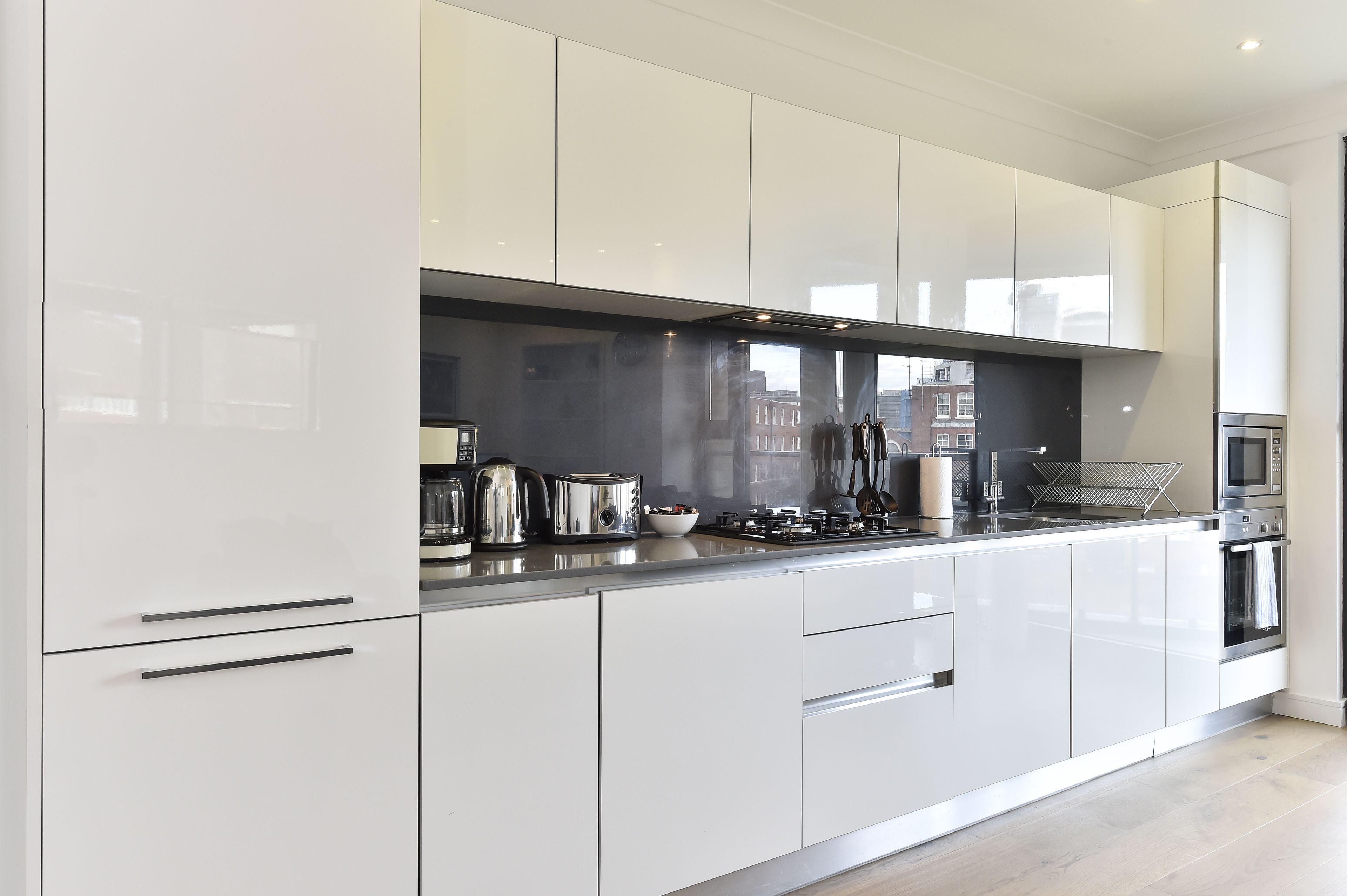 A modern kitchen with white cabinets, stainless steel appliances, and a black backsplash.