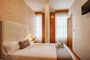 A hotel room with a large bed, a bedside table with a lamp, a nightstand, and a wall-mounted TV. - Hostal Zahara (Ferrol)