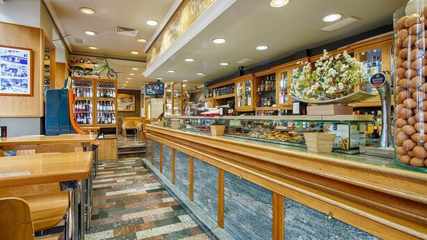 A restaurant with a long counter, wooden cabinets, and a tiled floor. - Hostal Zahara (Ferrol)