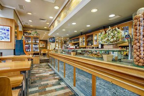 A restaurant with a long counter, wooden cabinets, and a tiled floor. - Hostal Zahara (Ferrol)