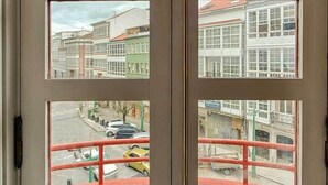 A door with multiple windows, each offering a view of buildings and a street. - Hostal Zahara (Ferrol)