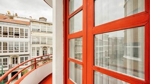 A balcony with a red railing overlooking a historic building with multiple windows and balconies. - Hostal Zahara (Ferrol)