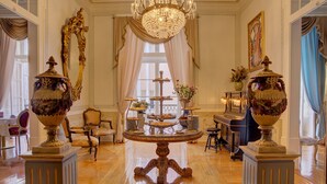 A grand room with a central ornate table, elegant chairs, and a chandelier. - Palácio das Especiarias (Lisbon)