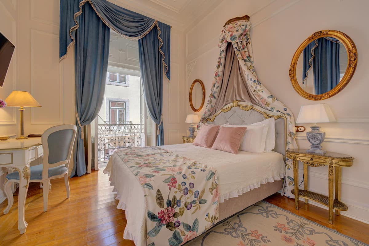 Een slaapkamer met een hemelbed, een bureau met stoel, en een raam met gordijnen.