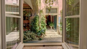 Une cour intérieure agrémentée de plantes en pot et un chemin de pierre menant à l’entrée d’un bâtiment.