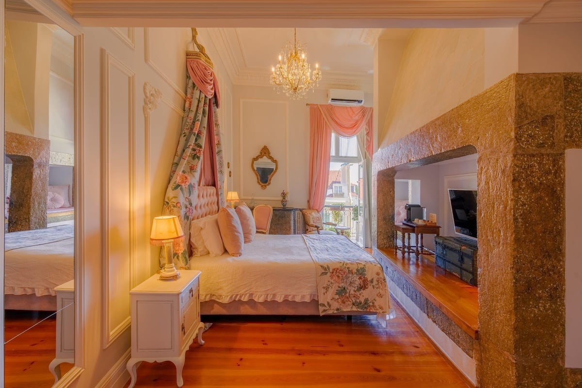 Een slaapkamer met een bed, nachtkastje, lamp en spiegel.