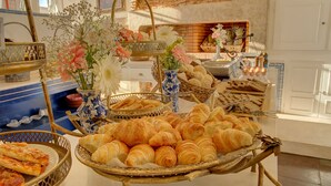 A buffet with various baked goods, including croissants and bread, arranged on a table with baskets and vases of flowers. - Palácio das Especiarias (Lisbon)
