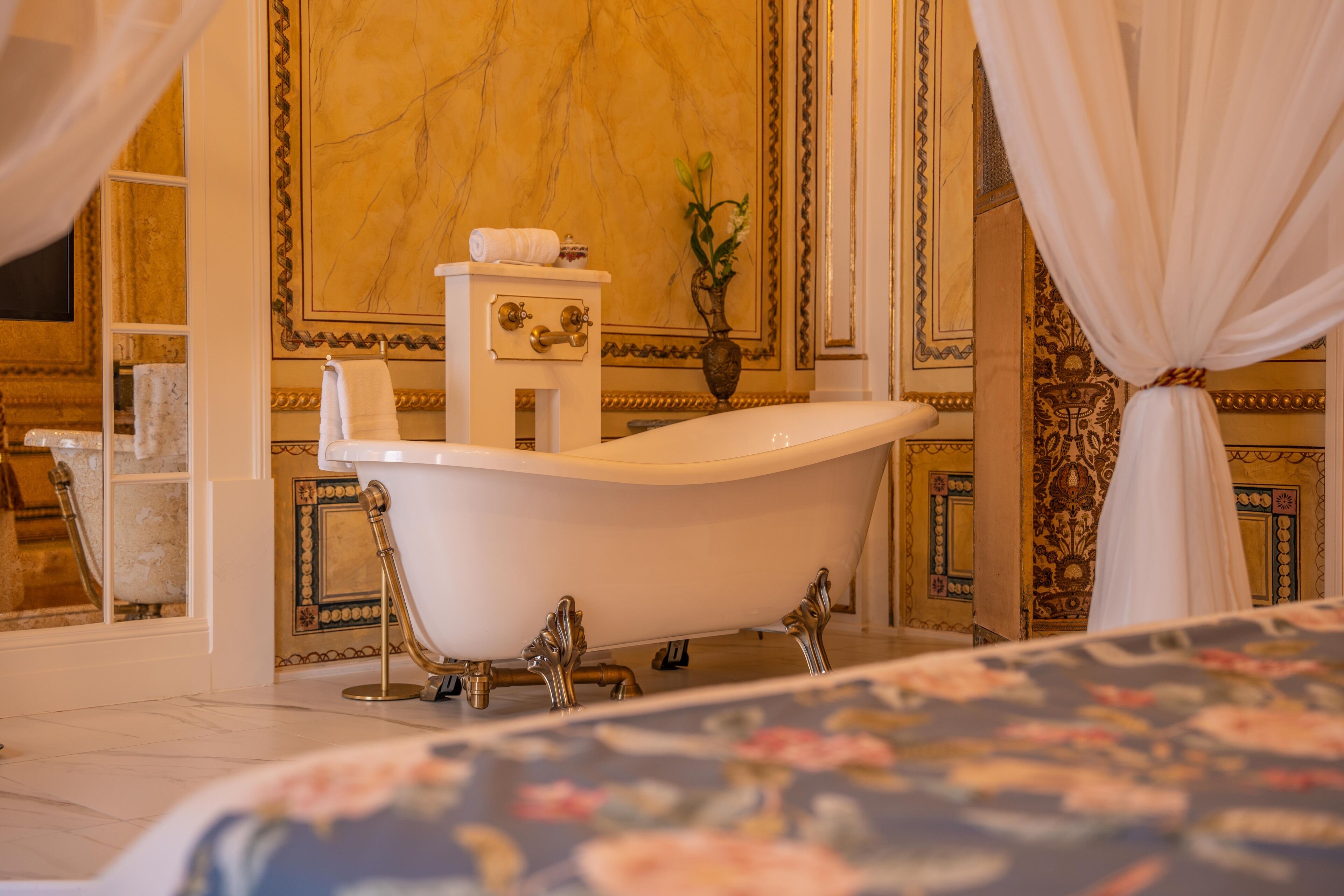 A luxurious bathroom with a freestanding bathtub, marble walls, and ornate decor.