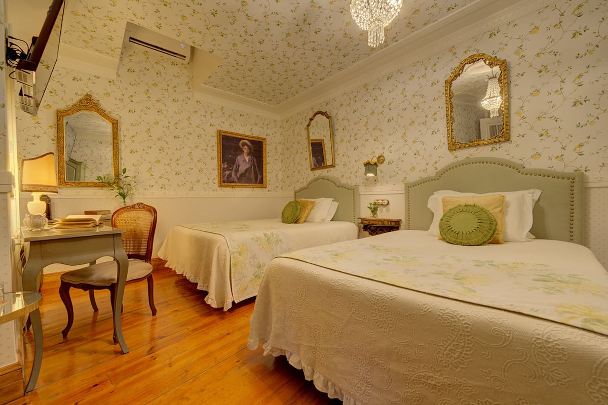 Een kamer met twee bedden, een bureau en een stoel. Twee spiegels en een kroonluchter zijn aanwezig.