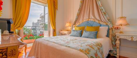 A bedroom with a canopy bed, floral bedding, and a view of the city through large windows.