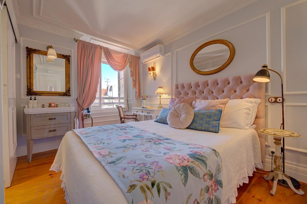 Een slaapkamer met een groot bed, een kaptafel met spiegel en een raam met gordijnen.