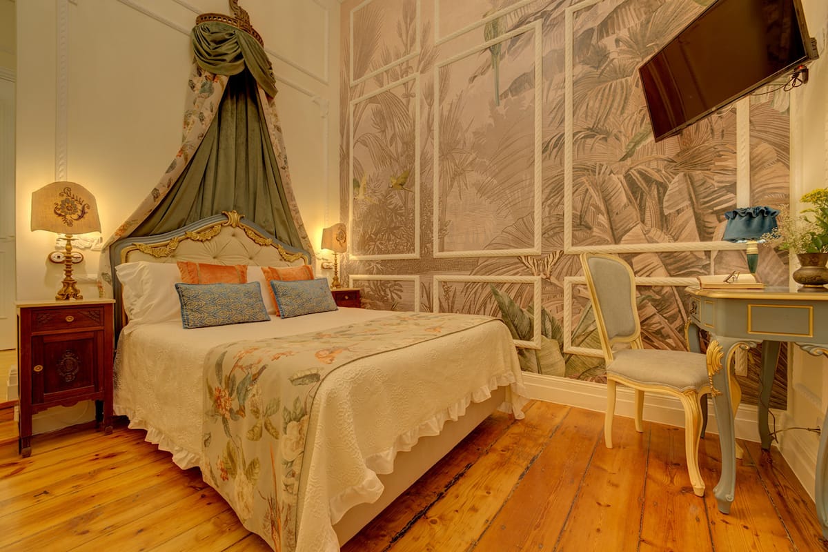 Een slaapkamer met een hemelbed, een bureau en een stoel.